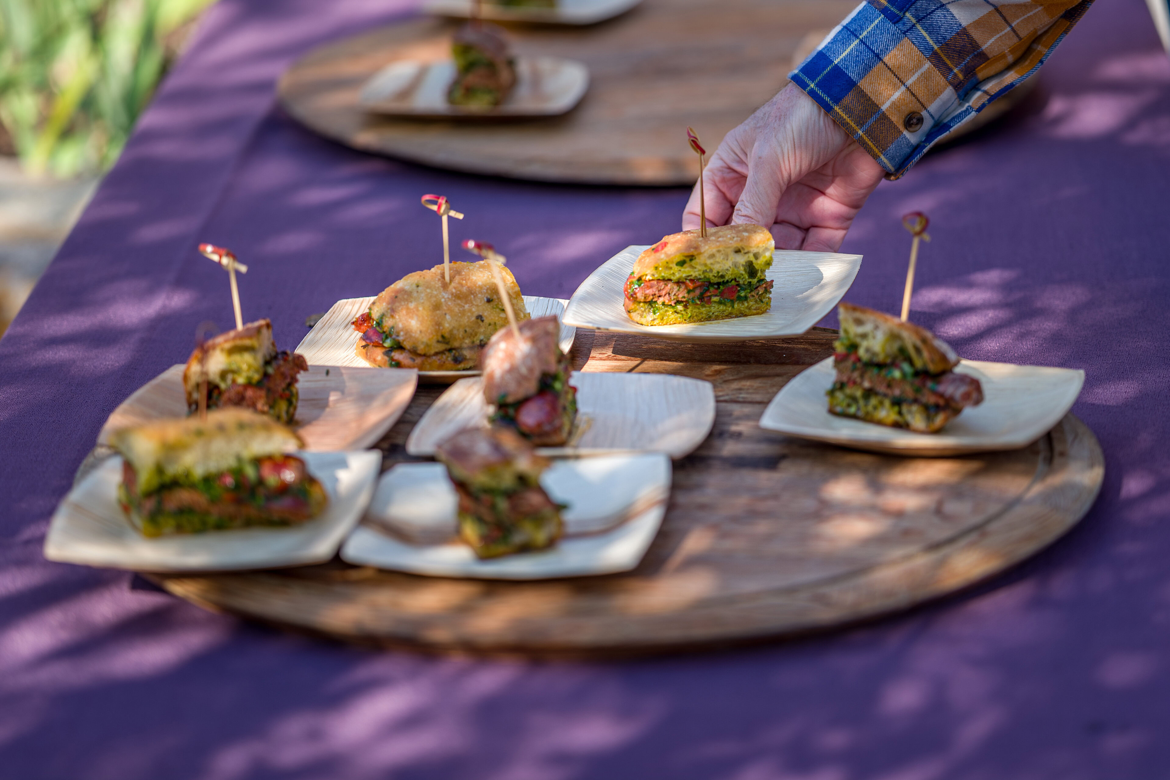 Grilled Argentinian chorizo sausage sandwiches served on small plates at outdoor event.