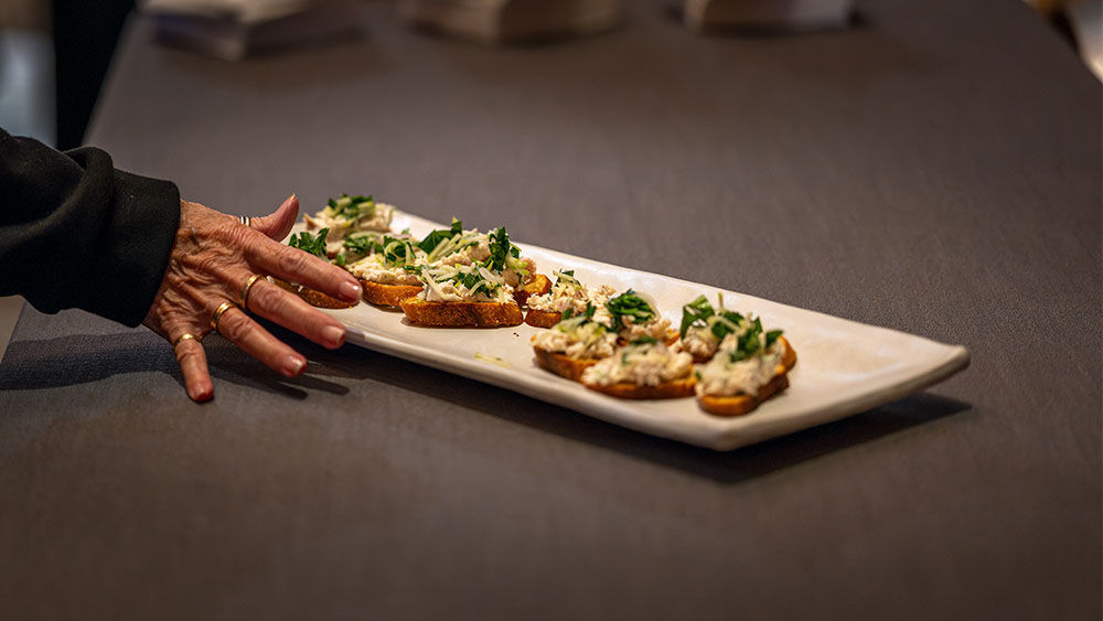 Delicate crostini topped with smoked sturgeon pâté, pickled fennel, and apple salad on a white serving platter.