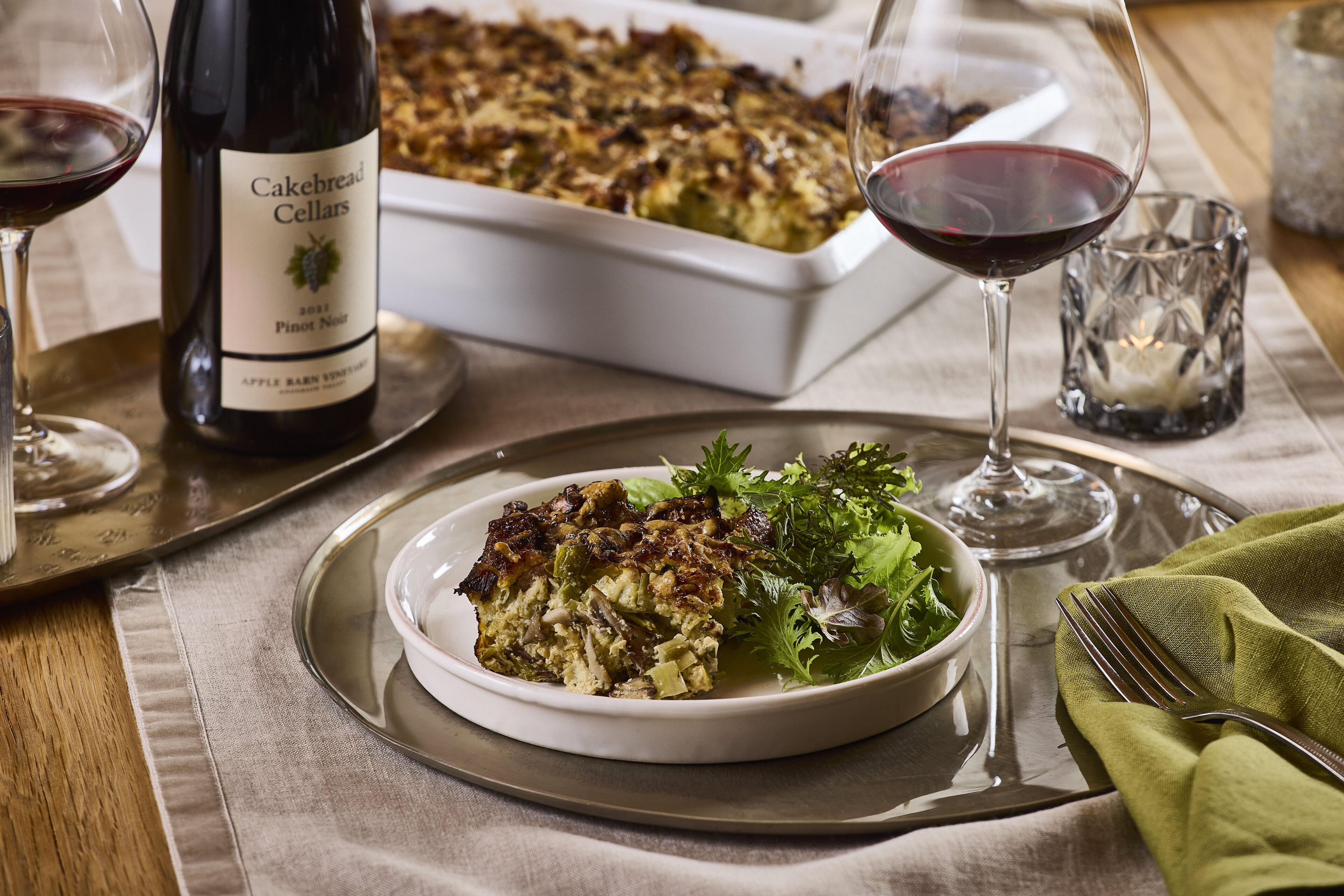 Cakebread Cellars wine and a serving of vegetable casserole with fresh herbs on a dinner table.