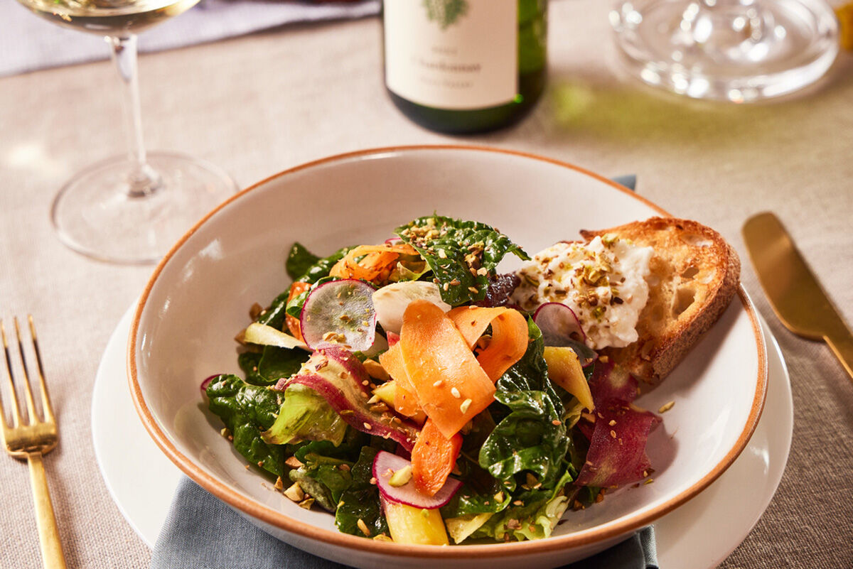 Fresh baby spinach salad with heirloom carrots, radishes, and burrata cheese served with toasted bread and pistachio dukkha.