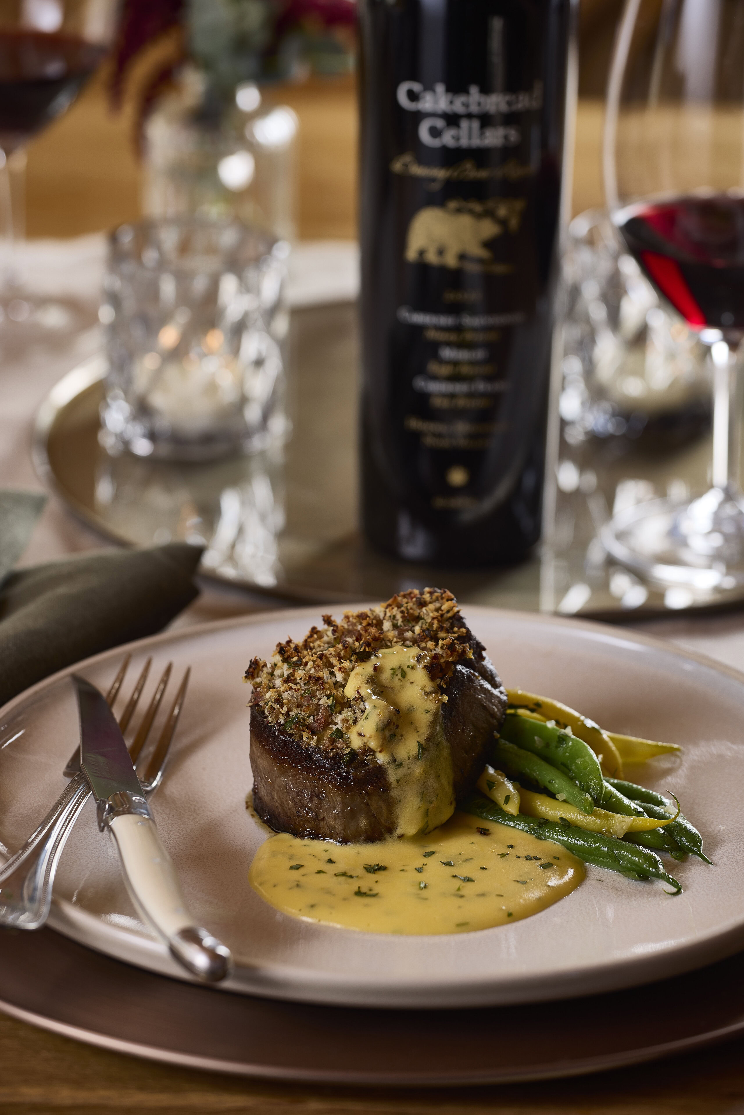 A lush bacon-horseradish crusted filet mignon served with green beans and a creamy sauce on a white plate at Cakebread Cellar.