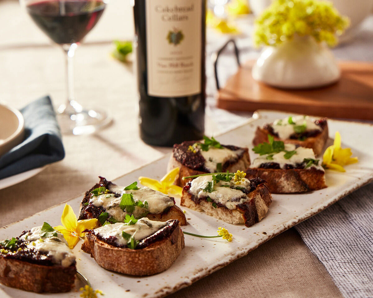 Bruschetta with Black Mission Figs, Point Reyes Blue Cheese, and fresh herbs on a rustic serving platter.