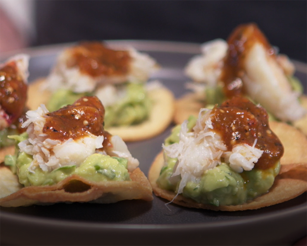Delicious crab tostadas topped with guacamole, shredded crab meat, and tomatillo salsa on crispy tortilla chips.