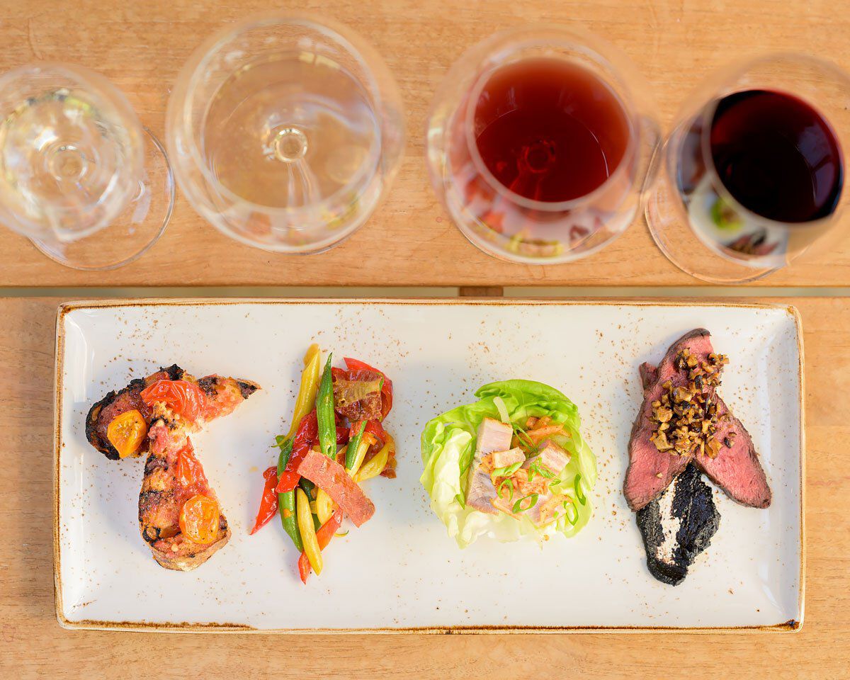 A delicious wine and food pairing featuring grilled meat, vegetable salad, lettuce wrap, and seared beef with toppings, serve.
