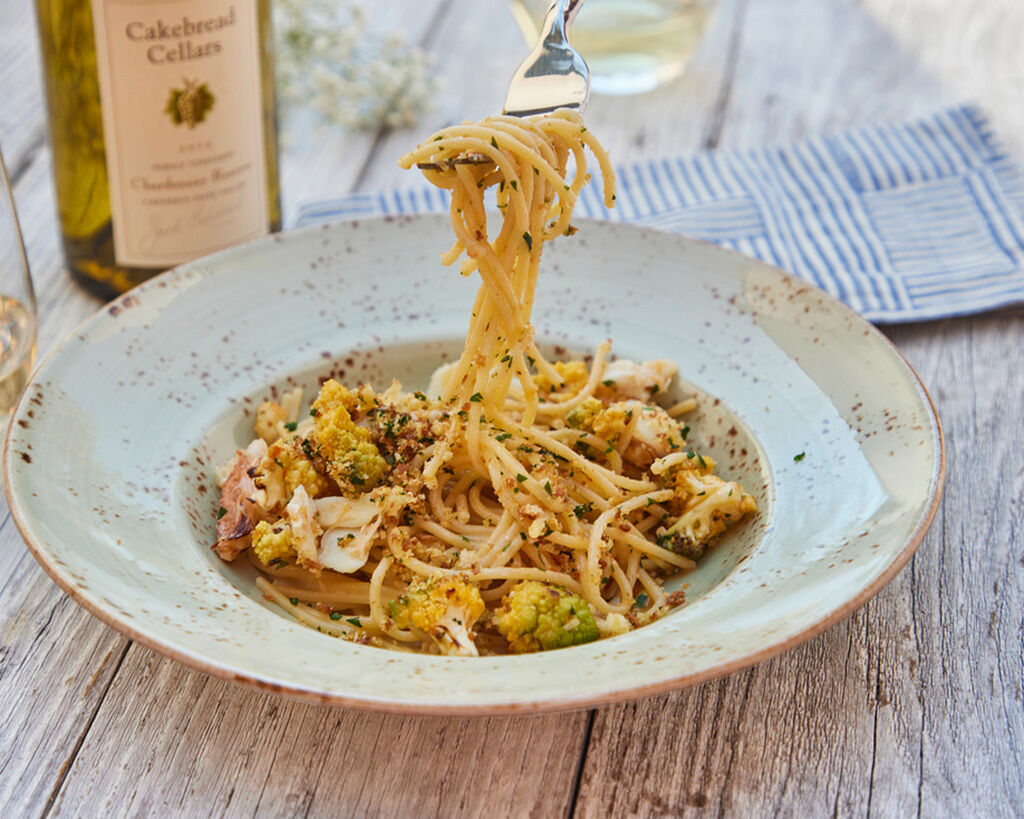 Delicious spaghetti with Dungeness crab, Romanesco broccoli, and garlic breadcrumbs served on a rustic ceramic plate.