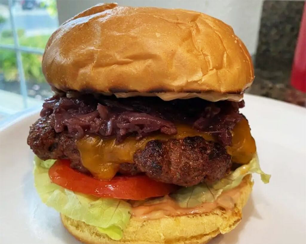A delicious steakhouse cheeseburger with caramelized onions, lettuce, tomato, and melted cheese in a soft bun.