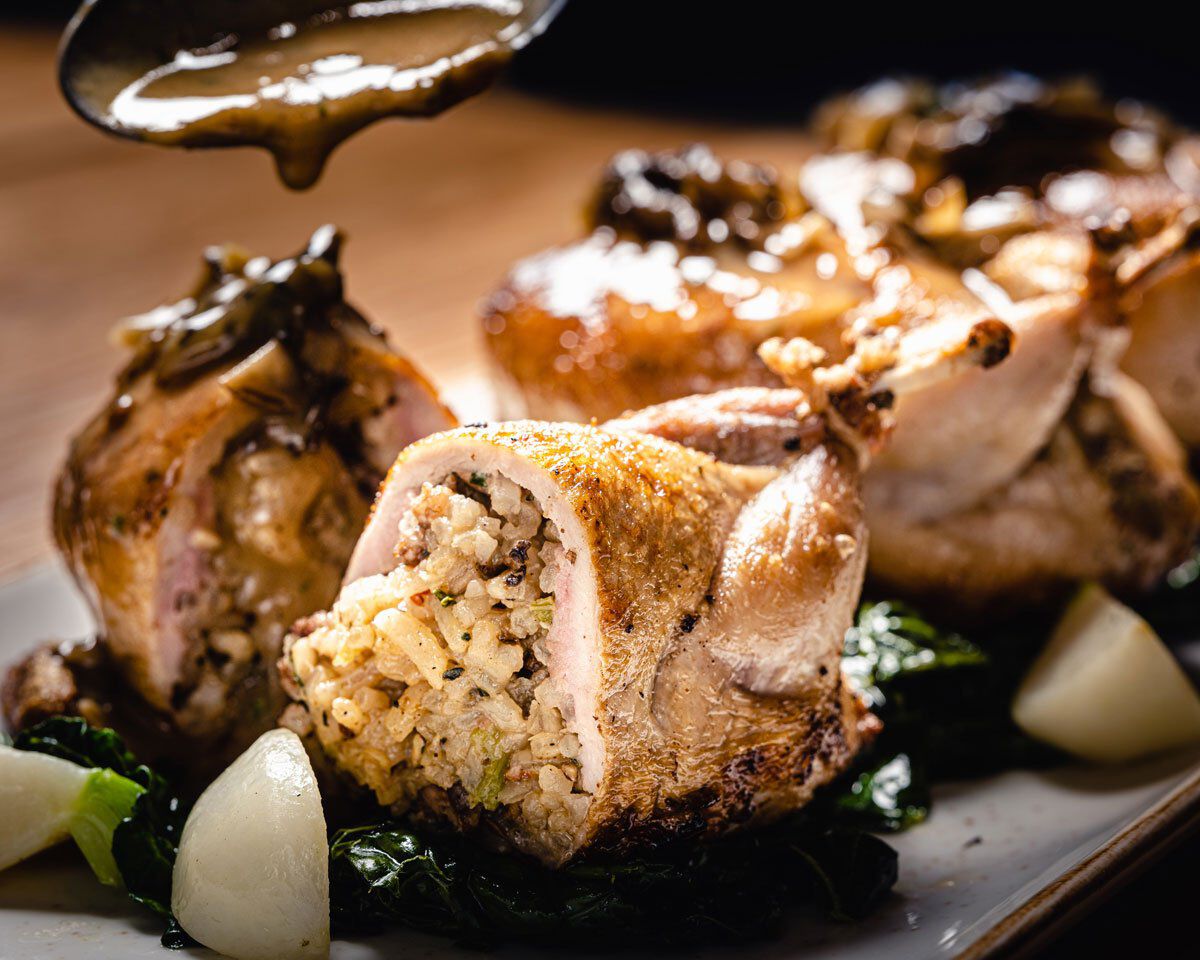 Succulent stuffed quail with rice and mushroom gravy, served with garlic and greens, showcasing a gourmet dish from Cakebread.