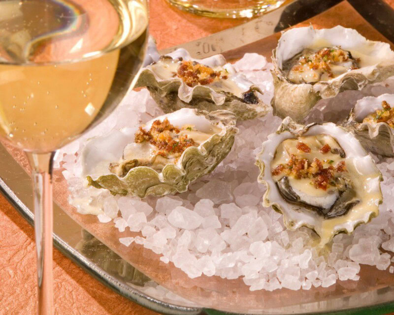 Fresh oysters on ice with a glass of white wine, served as part of a culinary experience at Cakebread Cellars.
