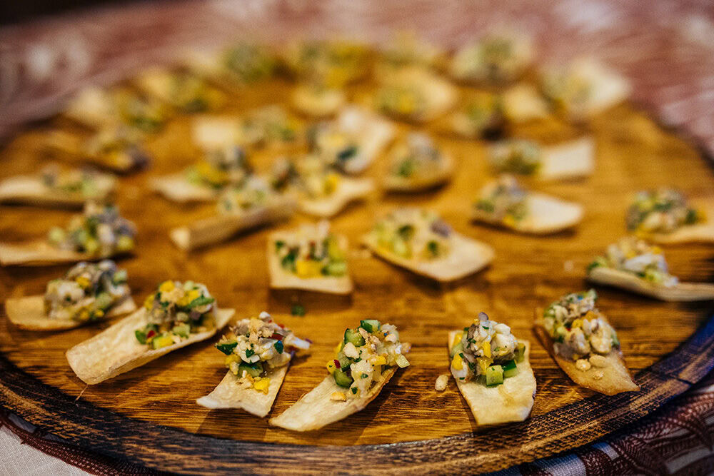 Assorted canapés with cheese, herbs, and spices on a wooden serving platter for cooking with Cakebread: World of Spices.