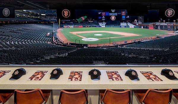 A baseball stadium with San Francisco Giants branding, empty seats, and a view of the field from a suite level.