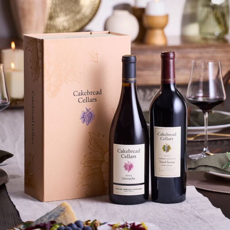 Cakebread Cellars wine bottles with gift box on a dining table, red and white wine, elegant presentation.