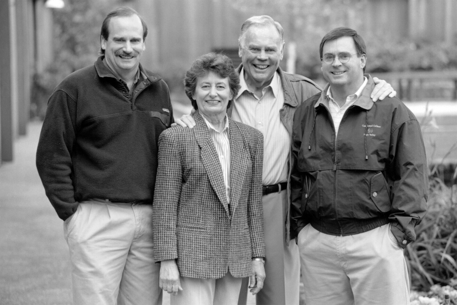A woman and three men smiling outdoors at Cakebread Cellars winery in Napa Valley.