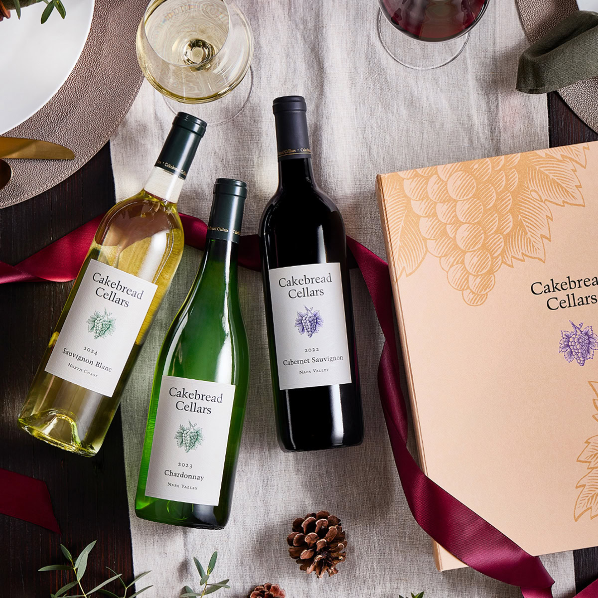 Assorted Cakebread Cellars wine bottles with a gift box on a table setting, showcasing premium Napa Valley wines for special.