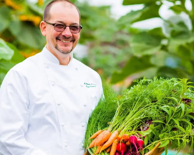 Brian Streeter posing with freshly harvested vegetables and herbs at Cakebread Cellars farm, showcasing organic produce for winemaking and culinary use.