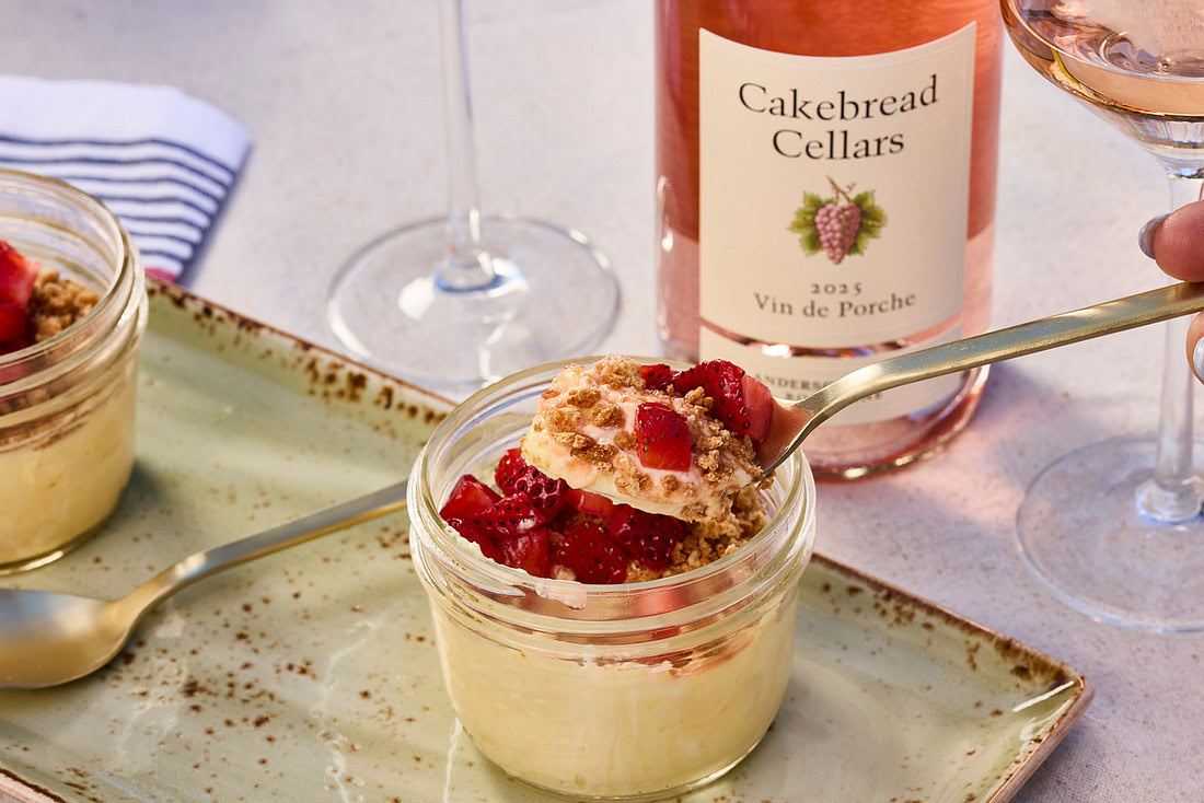Spoon scooping semifreddo with strawberries on the top and rose wine the background.